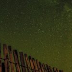 A fence with wooden posts and a starry night sky
