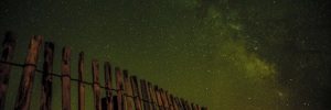 A fence with wooden posts and a starry night sky