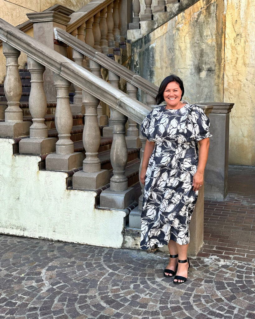 Woman in a black and white floral dress in front of architecturally beautiful steps.