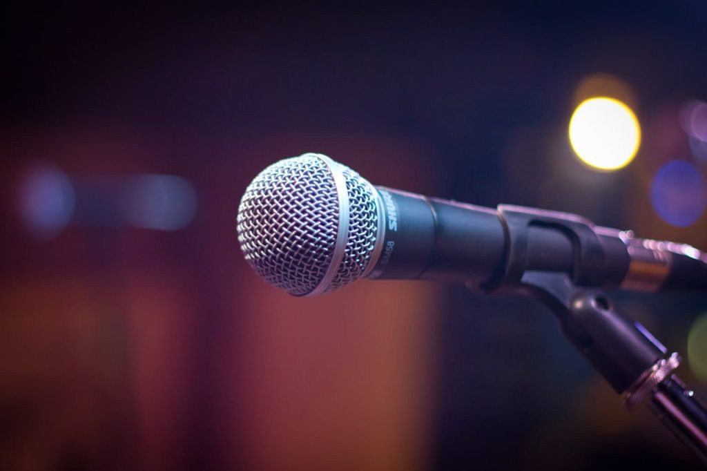 black-and-gray-microphone-164829 Dynamic microphone on stand with blurred stage lights in background.